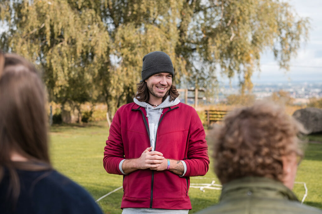 Trainer spricht mit Teilnehmenden eines Teamevents am Heubergturm bei Freiburg