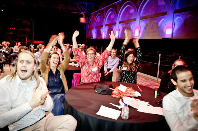 jubelnde Menschen sitzen an einem Tisch bei einem indoor Teamevent